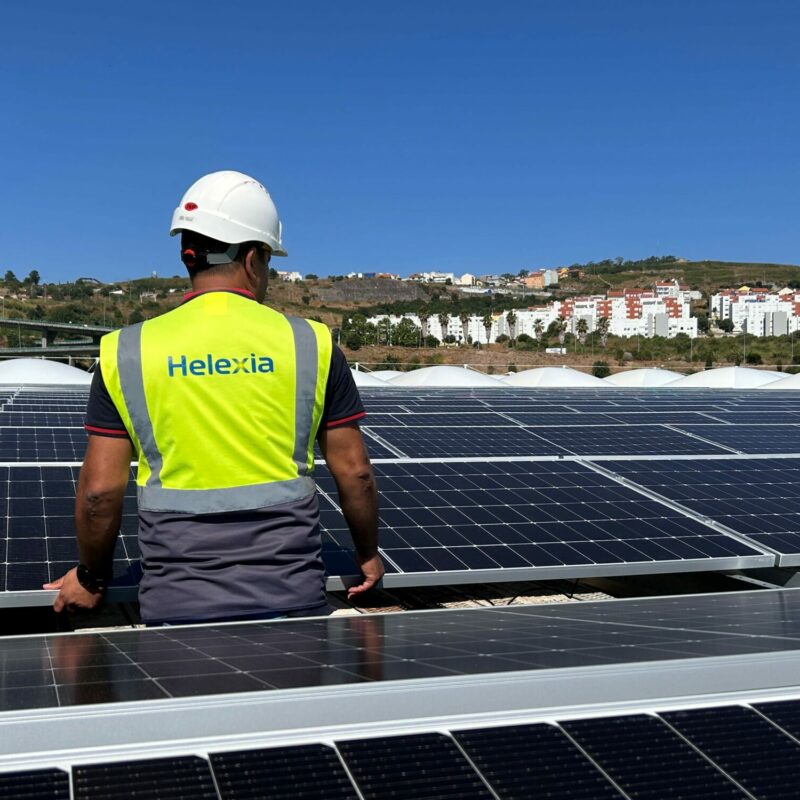 Técnicos de Helexia España instalan un panel solar sobre la cubierta de una nave industrial para un proyecto de autoconsumo fotovoltaico.