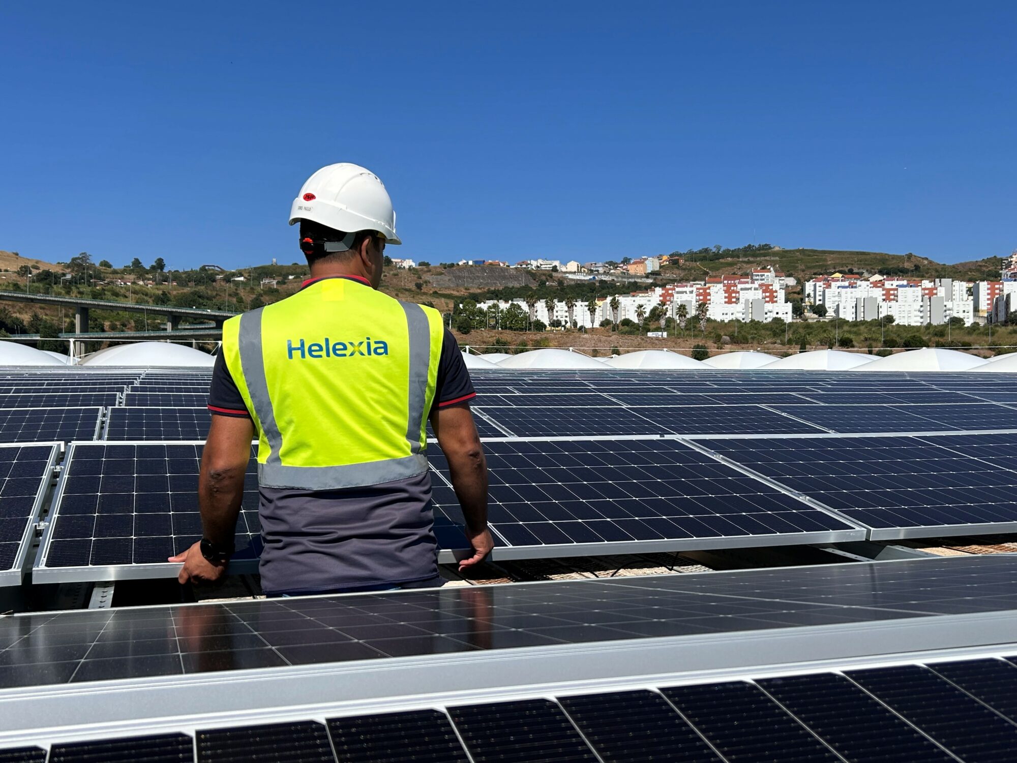 Técnicos de Helexia España instalan un panel solar sobre la cubierta de una nave industrial para un proyecto de autoconsumo fotovoltaico.